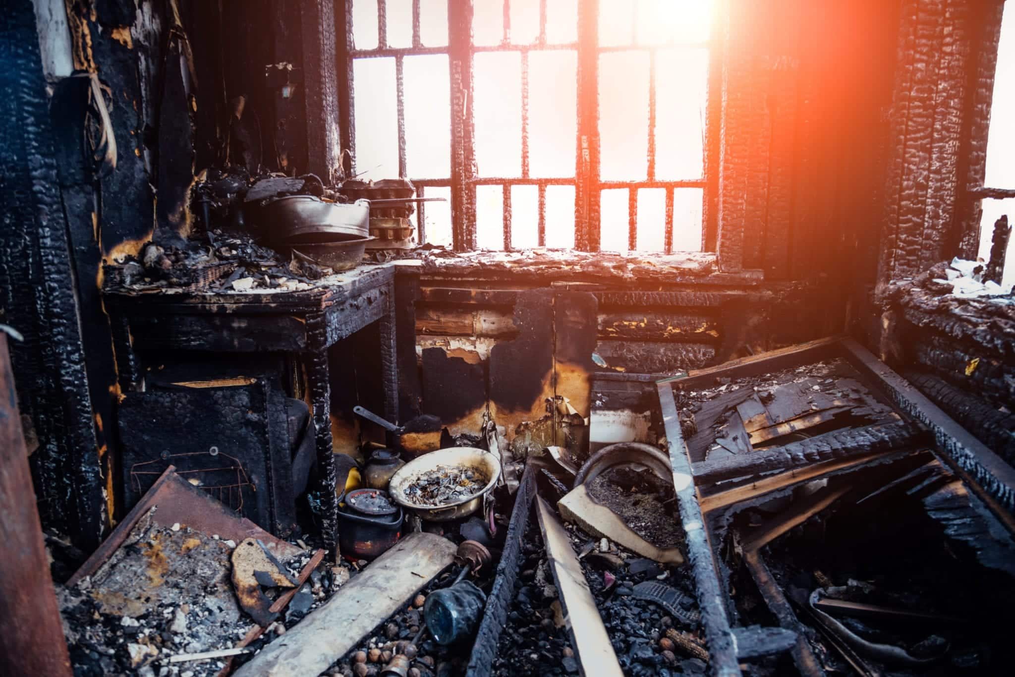 Burnt house interior. Burned kitchen, remains of furniture in black soot Fire damage attorney