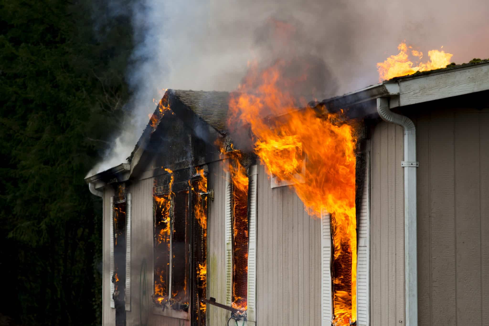 Flames erupting from window in burning home Fire damage lawyer